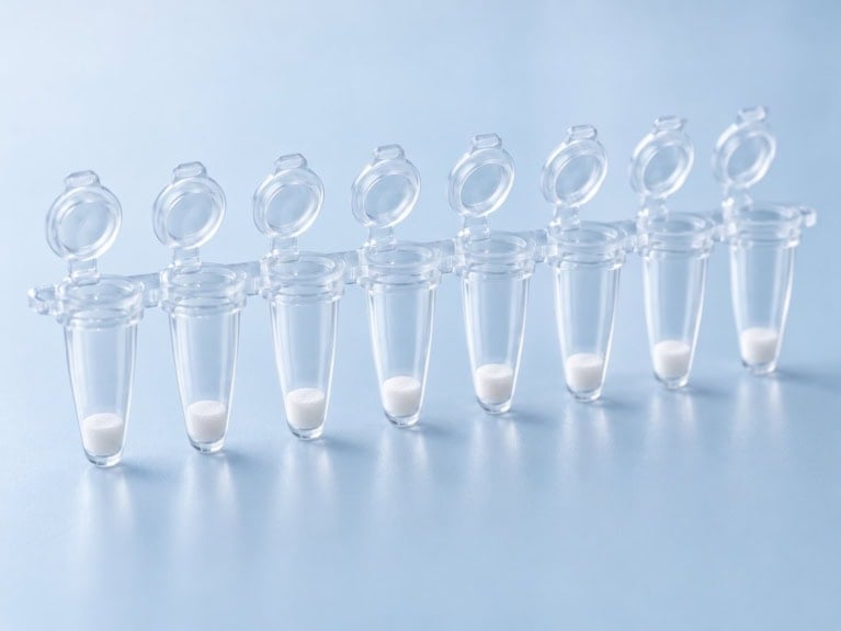 8-tube PCR strip with caps open and a white lyophilized reagent cake in each tube, dried in situ